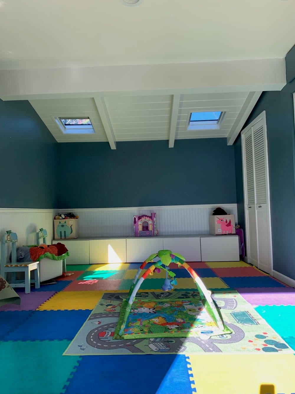 Bright indoor playroom with colorful foam mats and natural skylights